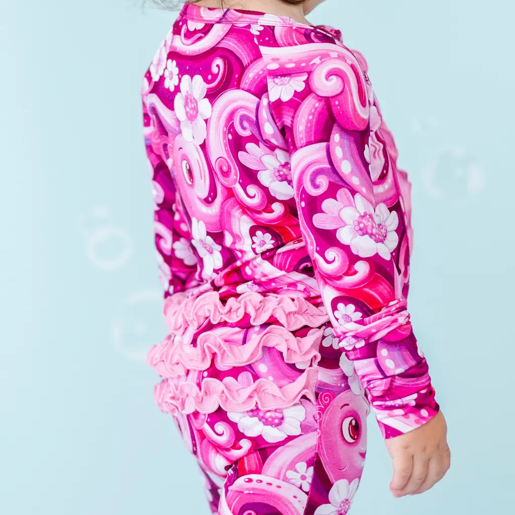 Child wearing a pink and white patterned outfit on a light blue background